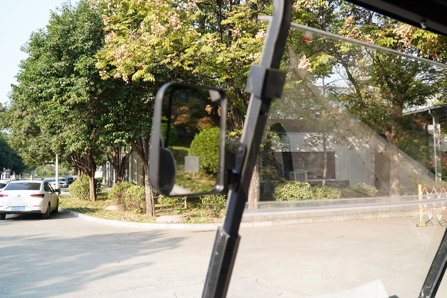 View from inside a Golf Cart showcasing trees and nearby vehicles on a sunny day