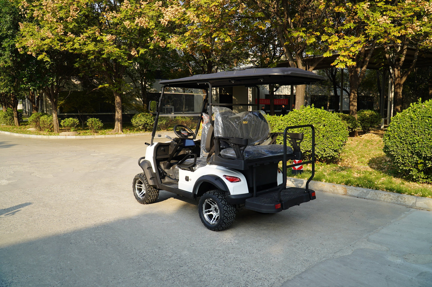 White Golf Cart parked on a sunny day surrounded by trees and greenery