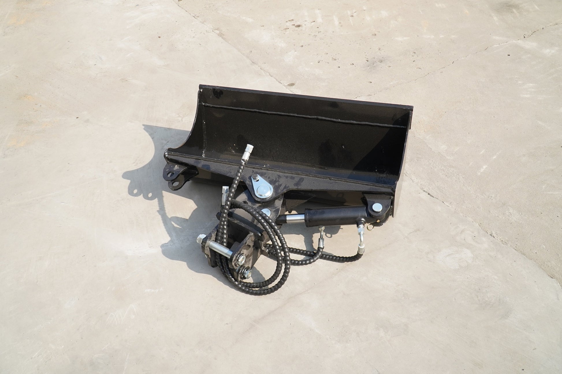 Rippa Australia Excavator Tilt Bucket attachment in black with hydraulic hoses on concrete floor
