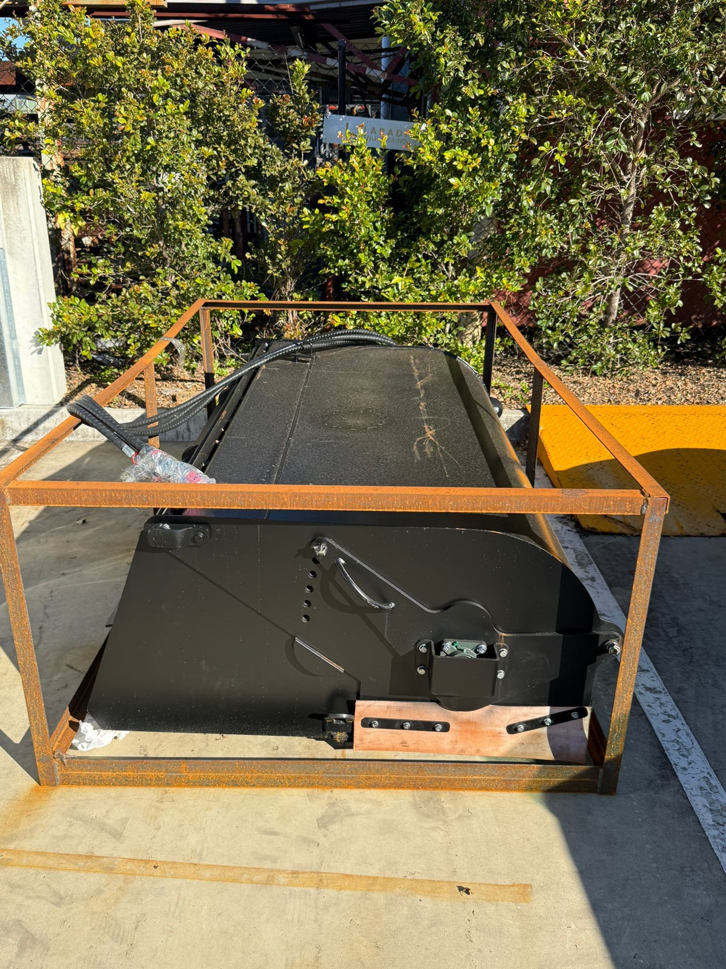 Labadi Engineering Hydraulic Skid Steer Sweeper in black metal frame on concrete floor outdoors