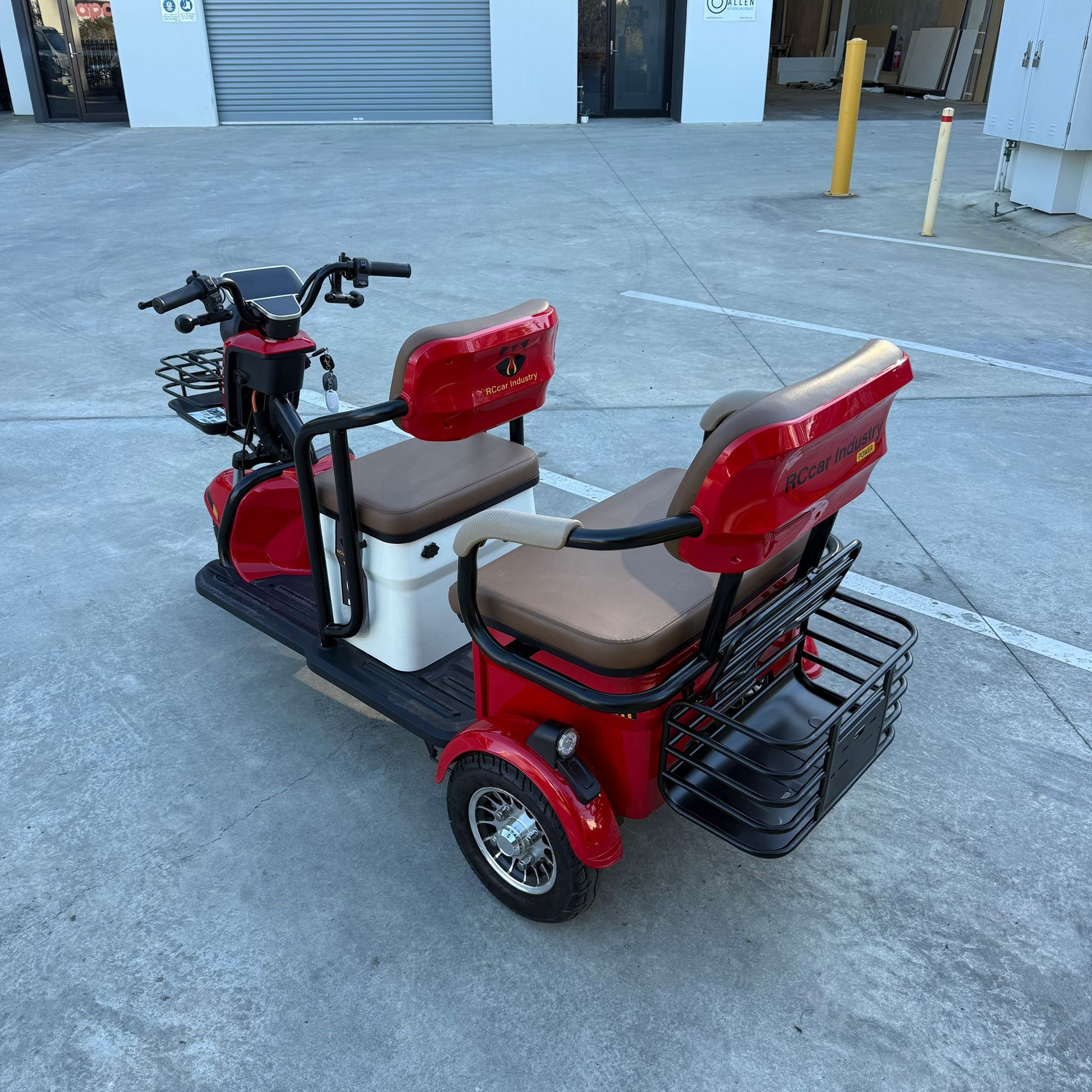 Red Labadi Engineering Wheel Trike with two cushioned seats and rear storage basket on concrete surface