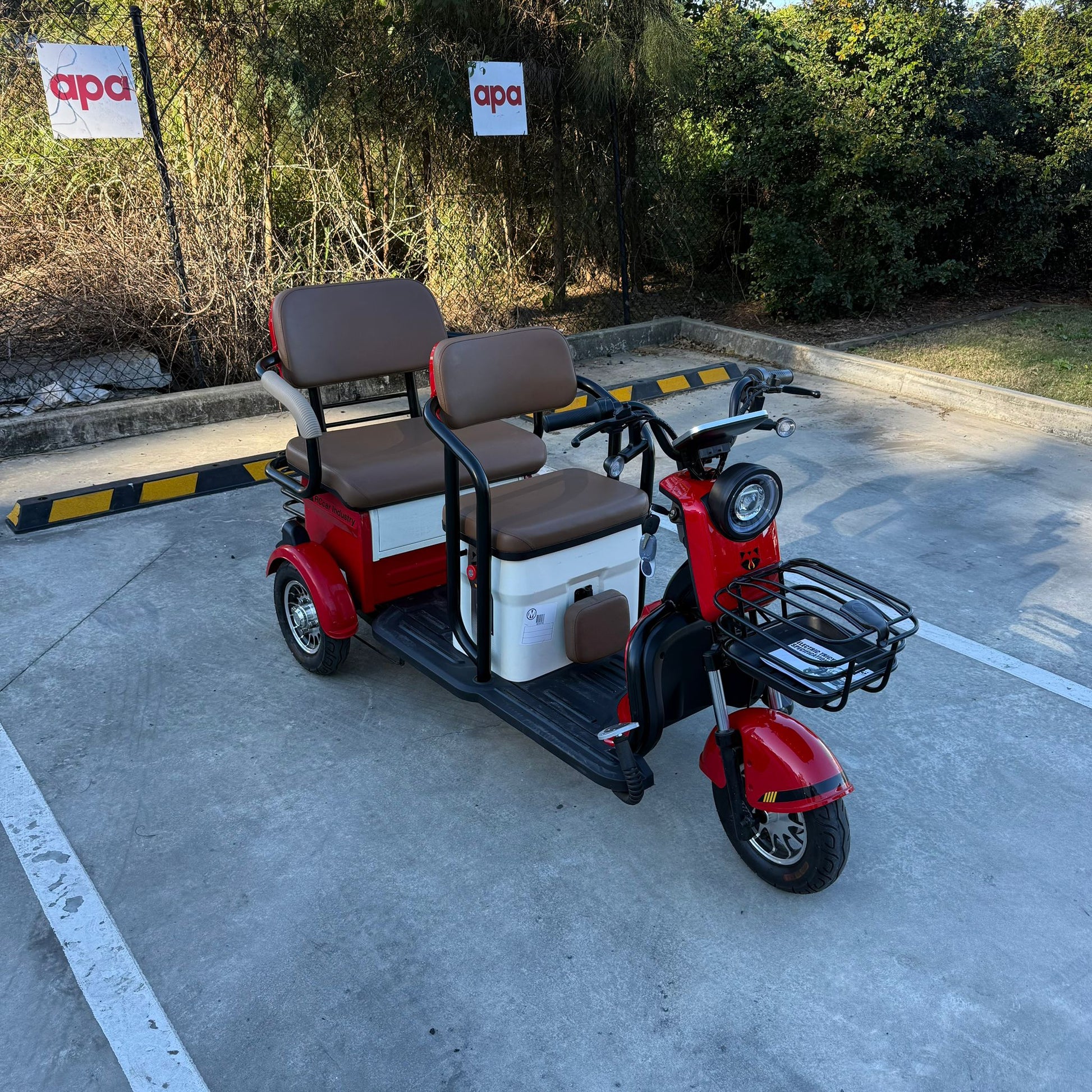 Labadi Engineering red Wheel Trike with two brown seats and front cargo rack parked outdoors